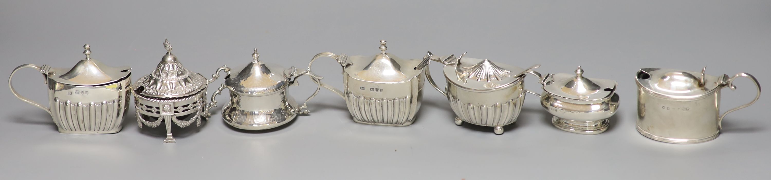 An ornate silver circular mustard with ruby glass liner and six other silver mustards, Victorian and later, approx 12oz